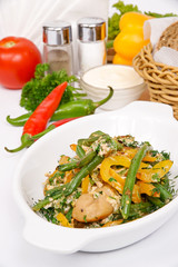 French bean with mushrooms decorated with parsley and dill in white plate on a background of vegetables, sour cream and cutlery
