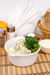 Quenelles of pike-perch are decorated with parsley and dill in white plate on a background of vegetables and cutlery