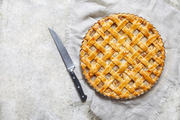 Apple pie tart with raisins, nuts and cinnamon on white kitchen background. Flat lay.