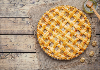 Apple pie tart with raisins, nuts and cinnamon on vintage wooden background texture. Rustic style. Top view