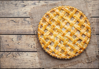 Apple pie tart with raisins, nuts and cinnamon on vintage wooden background texture. Rustic style. Top view