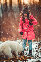Happy girl with Samoyed dog in winter forest