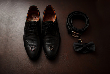 Brown leather men's shoes with accessories and wedding rings. Set of groom.