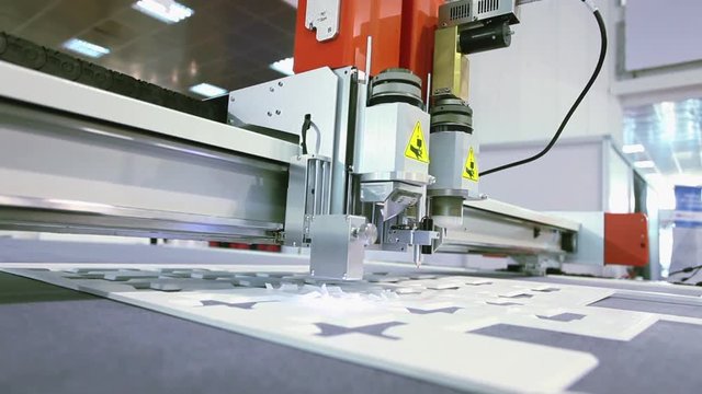 Computer controlled CNC cutting machine, cutting plastic foam, making small boxes form; close up, camera mounted at machine; slight vibrations; 