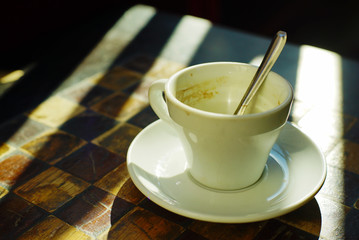 An empty cup of coffee on a chessboard.