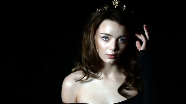 Portrait of a gorgeous girl with a decoration on the head in the shape of a crown. Long hair. In a Studio on a dark background