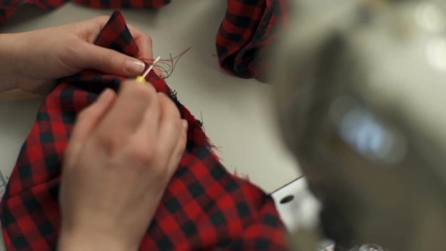 A young woman unpicking a piece of cloth using a ripper