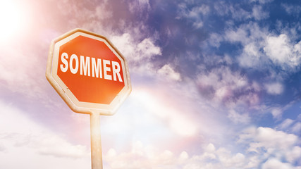 Sommer auf rotem Stoppschild vor blauem Wolkenhimmel
