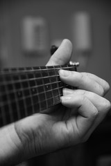Close up view of a young guy playing a guitar, black and white image.