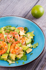 Shrimp, Avocado, Apple and Onion Salad. Grilled prawns on blue plate.