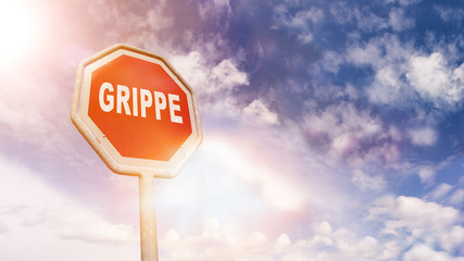 Grippe auf rotem Stoppschild vor blauem Wolkenhimmel