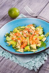 Shrimp, Avocado, Apple and Onion Salad. Grilled prawns on blue plate.
