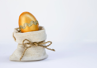 Orange Easter egg in canvas sack over white background