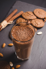 Chocolate smoothie with bananas and cookies on the dark wooden background. Toned image.