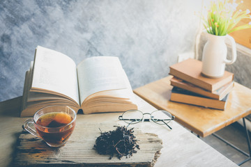 A cup of tea with tea leaf and book on table