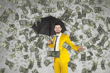 Young rich businessman standing in money rain