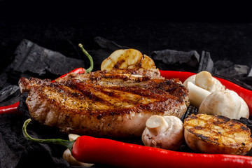 meat grilling on coal background with mushrooms, garlic and red pepper