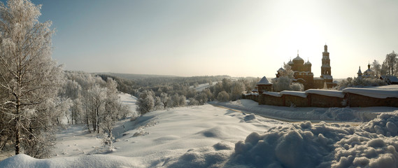 Orthodox monastery amidst winter forest panorama