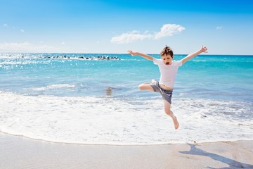 Fototapeta na wymiar Happy 7 years boy jumping on the beach