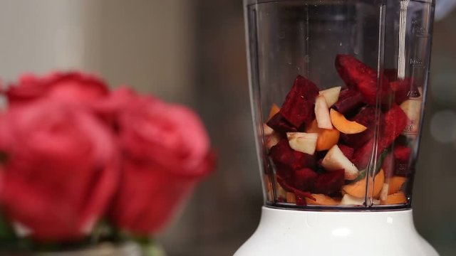 Woman adding vegetables and fruits into blender