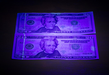 Money under ultraviolet light. Two twenty dollar bills under ultraviolet light