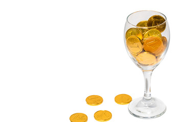 Glass of champagne with Overflowing golden coins, isolated on the white background