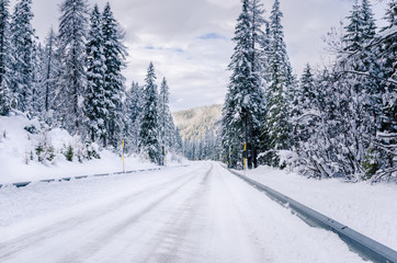 Deserted Snowy Mountain Road with Crash Barriers at the Sides on a Cloudy Winter Day