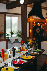 Wedding banquet table with dishes, vine and food. Loft, country and rustic style. Decoration. Arch with bulb garland on background