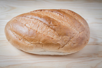 Large loaf of bread isolated on wooden table, food abstract.
