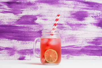 Raspberry lemonade with lice and ice in the glass on the wooden background