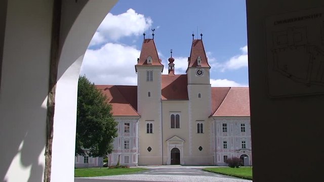 Offenes Eingangstor des Stiftes Vorau mit  Eisenzacken des ehemaligen Falltores und Blick auf die Stiftskirche (vertikaler Kameraschwenk)