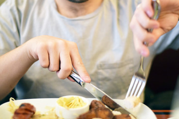 Male hands cutting and eating sausage