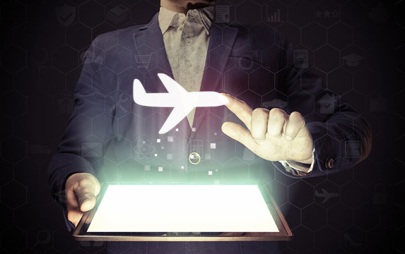 Image of a man with tablet in his hands with aircraft icon. Buying or booking online ticket. Travel concept, business flights, airplane delivery of cargoes and goods, logistics.