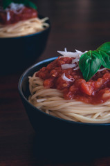 Italian spaghetti pasta bowl with red tomato sauce and flakes of parmesan cheese with basil leaves 