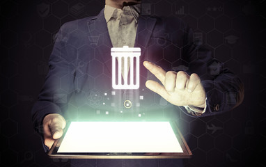 Image of a manl with tablet in his hands. He presses trash can icon. The concept of deleting files, contacts, putting in order, cleaning service etc - obrazy, fototapety, plakaty