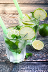 Mojito lime cocktail in bar on rustic table close up. Ingredients for making mojito. Summer refreshing drink. Image toned