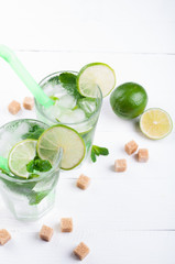 Mojito lime cocktail in bar on wooden backgroung with copy space. Ingredients for making mojito. Summer refreshing drink