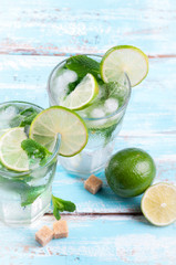 Fototapeta premium Mojito lime cocktail in bar on blue wooden backgroung with coppy space. Ingredients for making mojito. Summer refreshing drink