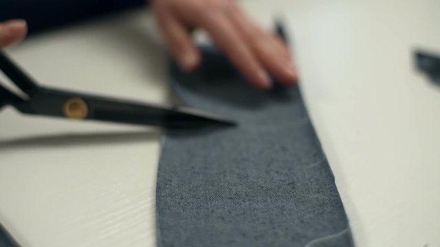 Seamstress cutting small pieces of tissue with sharp scissors in the workshop