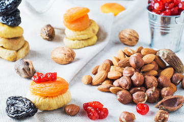 Mix of dried fruits and nuts, almonds, hazelnuts, dried cherries, dried apricots, figs and prunes on white wooden background. Healthy and wholesome food. The concept of natural organic food, diet.