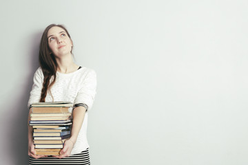 girl with long hair holding a pile of books and looking away. Get education or hobby books