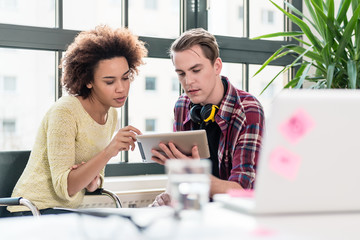 Two young employees watching a video on tablet PC in the office