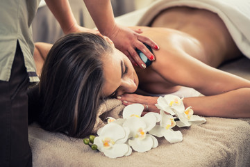 Woman enjoying the therapeutic effects of a traditional hot stone massage
