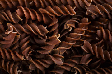 Background of colorful pasta texture close-up. Assortment of colorful macaroni. italian pasta. Variety of types and shapes of dry Italian pasta. Full background of dry uncooked macaroni.