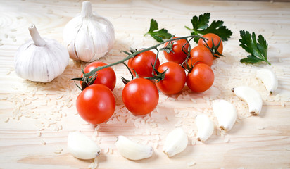 cherry tomatoes on a branch and garlic, parsley on the wooden table. food abstract