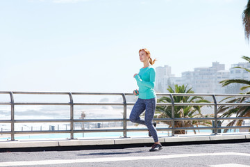 attractive female runner training on path outdoors by sea