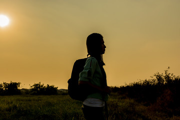 silhouette of backpack woman standing with sunset