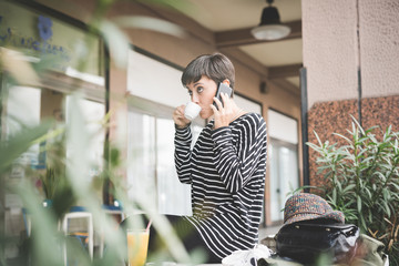 Young beautiful caucasian short hair woman having a coffee talking smart phone - communication, technology, call concept