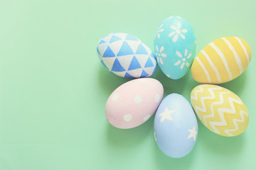 Pastel and colorful easter eggs with copy space on green background.
