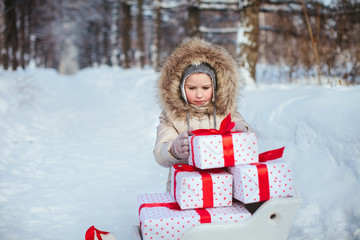 child open gifts in sledge in winter fores